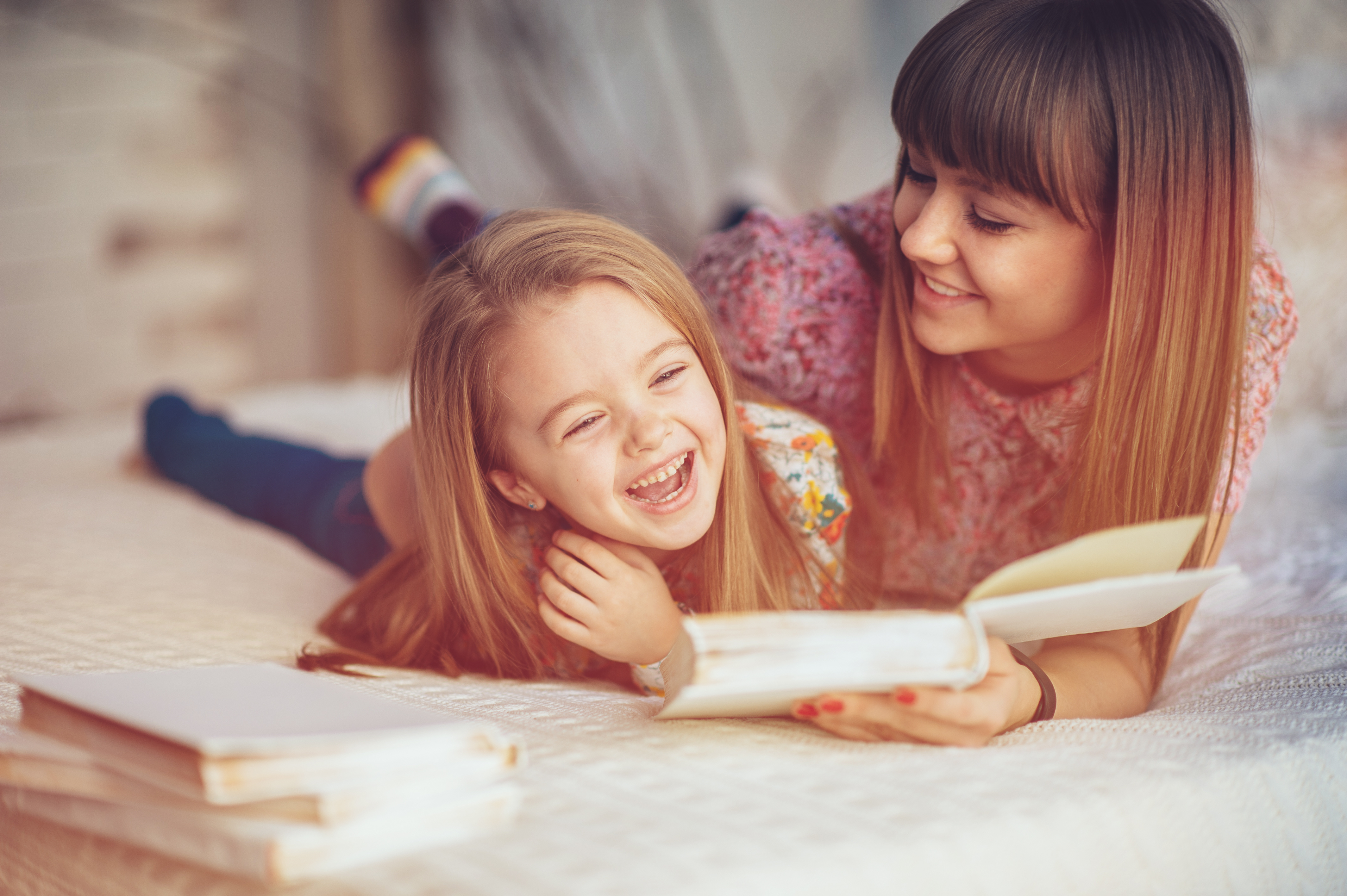 mom-reading-book-to-daughter-in-white-room