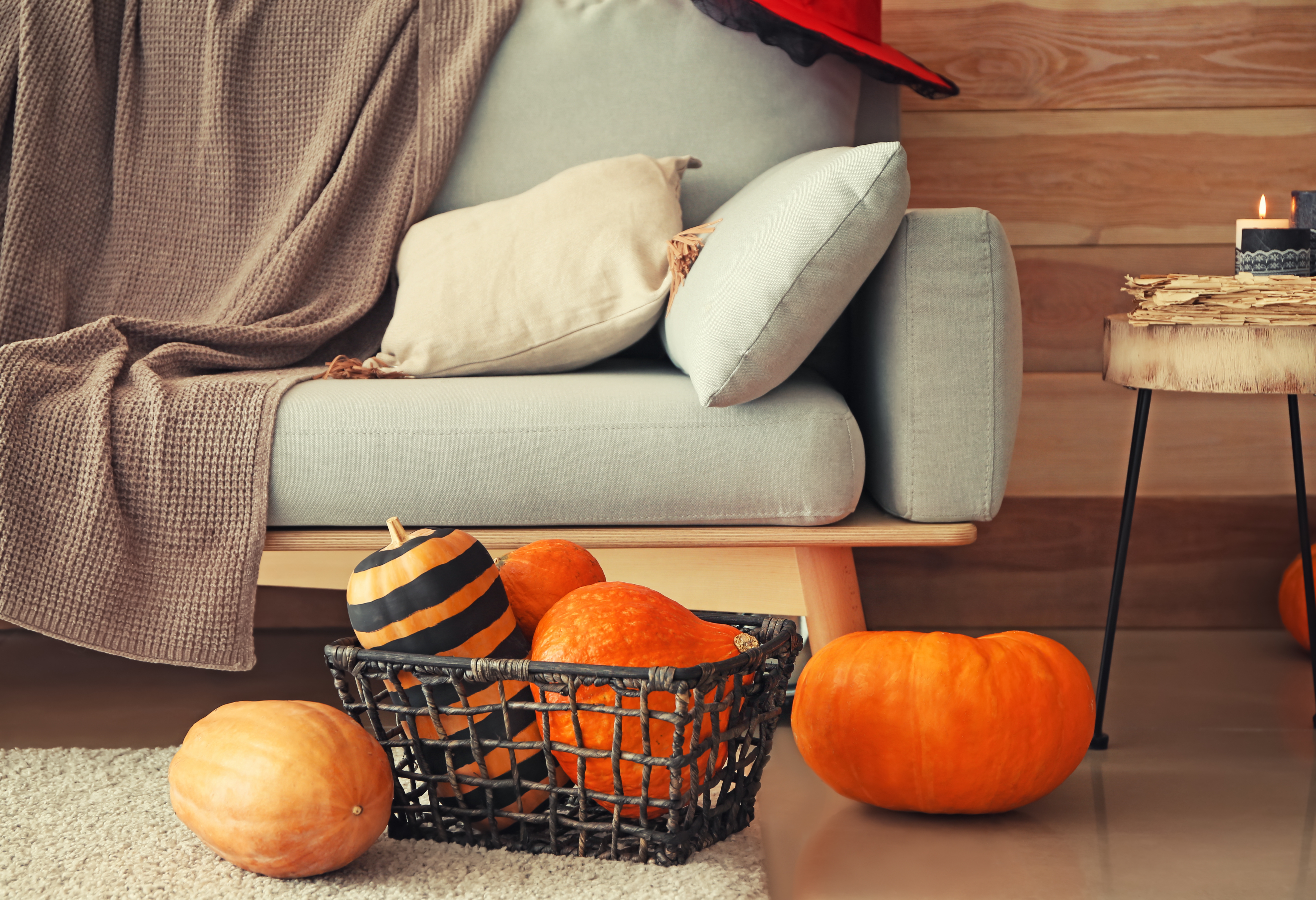 Basket with pumpkins prepared for Halloween party on floor in room