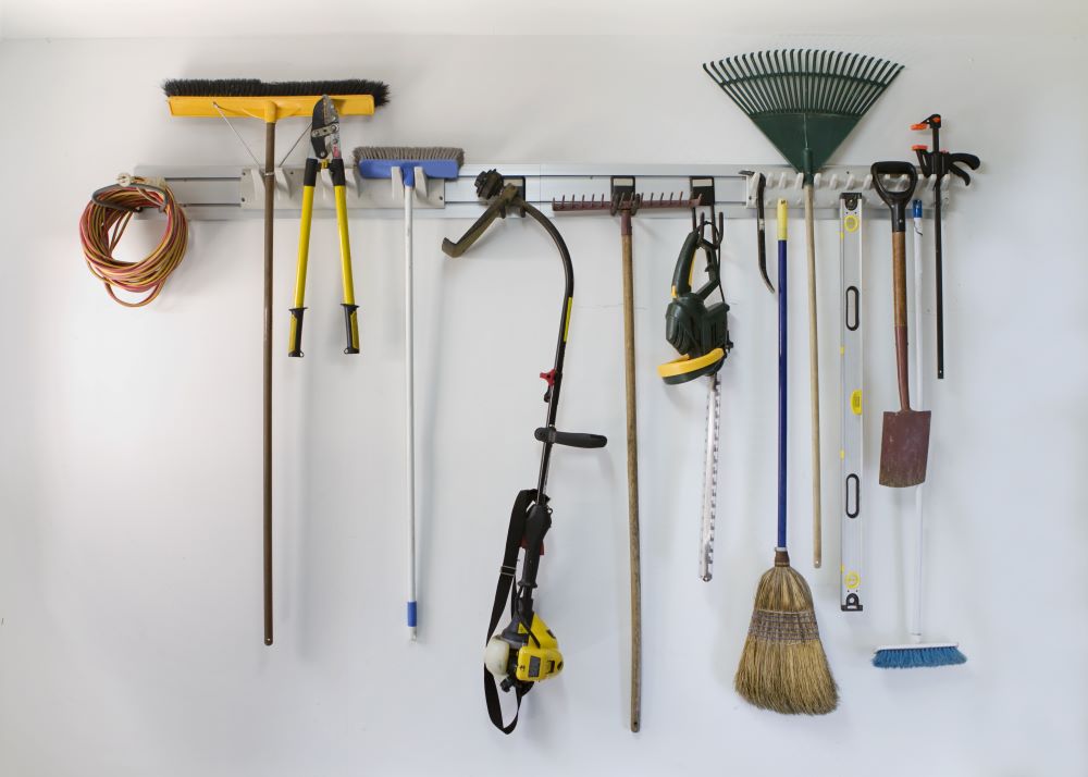 Hang brooms and rakes on wall in garage